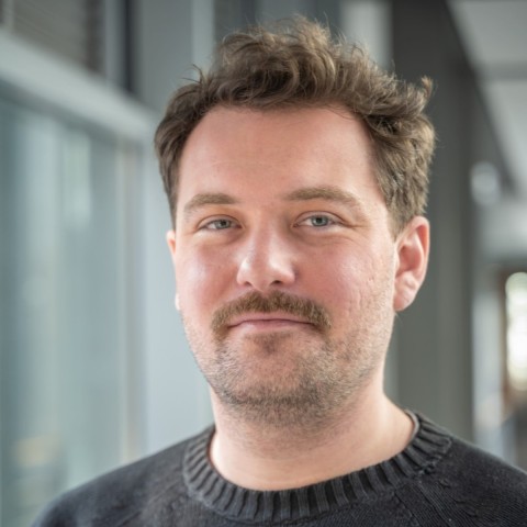 Jonas Ibel with moustache wearing black and smiling