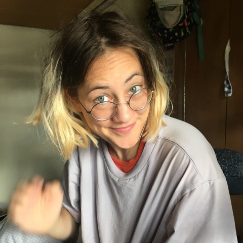 Amelie Goldfuß with blond brown hair and glasses waving