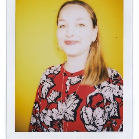 Katharina Meyer smiling with shining red lips in front of yellow background