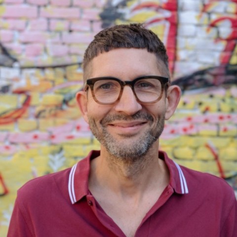 Eric steht vor einer bunt bemalten Wand