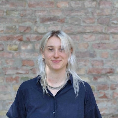 Foto von Marielle. Sie trägt ein dunkles Hemd und offene helle Haare.