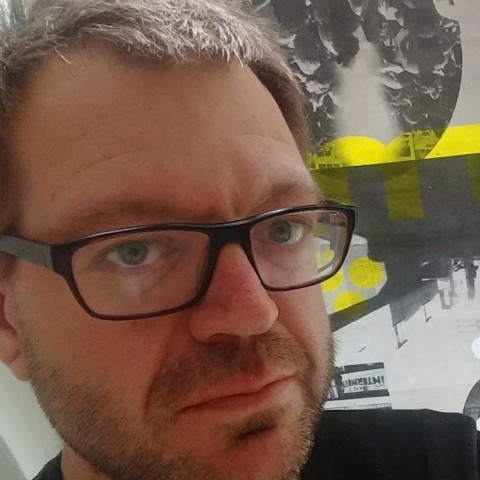 Foto von Alistair. Er trägt eine Brille und kurze Haare.