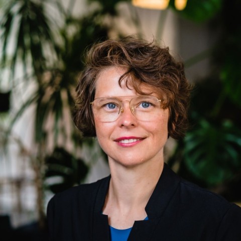 Foto von Julia. Sie trägt lockige kinnlange Haare und eine Brille.