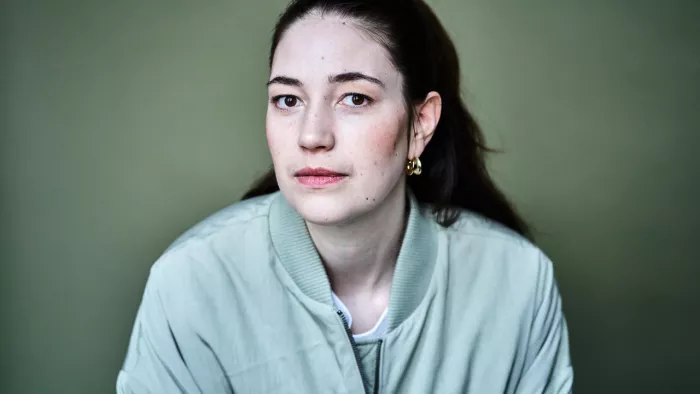 Ein Foto der Sprecherin. Sie trägt die Haare nach hinten zusammengebunden und eine mintgrüne Jacke.