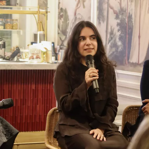 Cornelia sitting on a chair, talking into a microphone