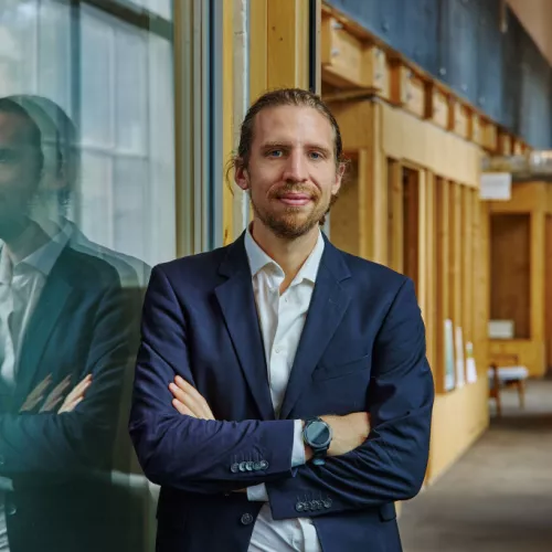 Dominik Campanella im blauen Anzug und verschränkten Armen im Porträit