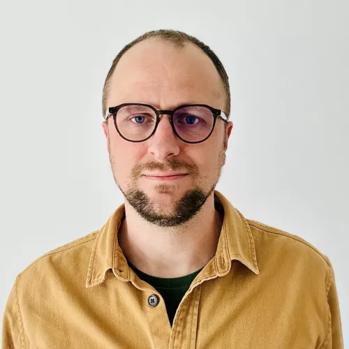 Potraitfoto von Heiko Klare mit Brille, kurzen Haaren und gelbem Hemd