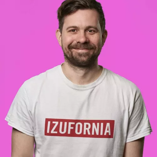 Mille in weißem T-Shirt mit "Izufornia"-Aufdruck vor hell-fliederfarbenem Hintergrund.