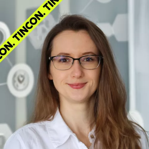 Frau mit langen, braunen Haaren und Brille lächelt