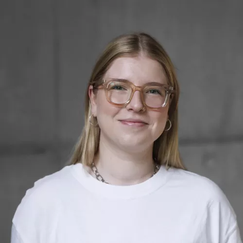 Das Bild zeigt eine blonde Frau mit Brille.