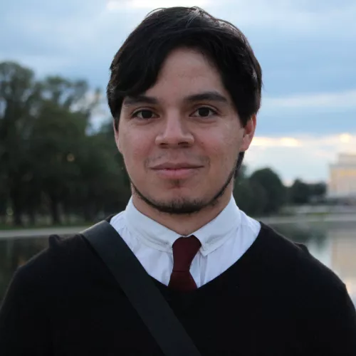 Portrait of Nelson Rauda Zablah. He is wearing a tie and a sweater.