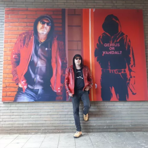Prof. Bob Coecke in a red jacket standing in front of two large Art canvases